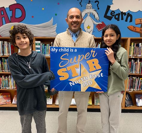  A man with two students holding a sign