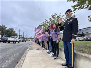 students with flags and veteran saluting