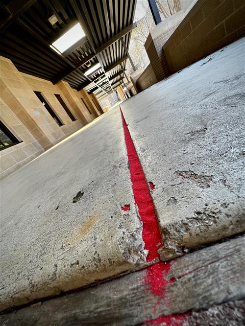 red sanding filling a crack in sidewalk
