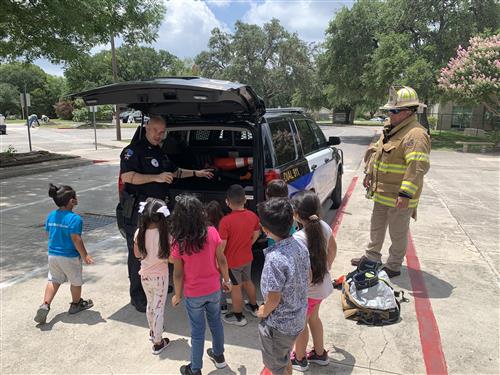 officer showing off his patrol car to students