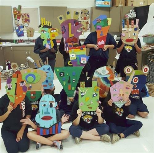 students wearing colorful cardboard masks 